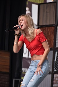 a woman in a red top singing into a microphone