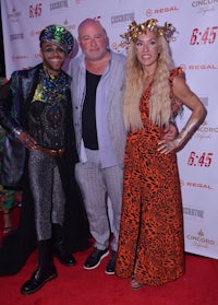 three people posing for a photo on a red carpet