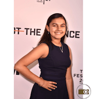 a girl in a blue dress standing on a red carpet