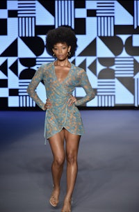 a black woman walking down the runway in a blue dress