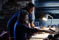 two men working at a desk in a dark room