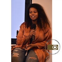 a woman is holding a microphone while sitting in a chair