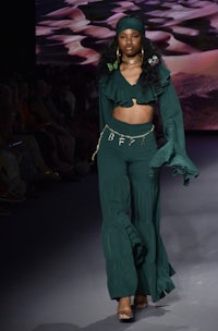 a model walks the runway in a green outfit