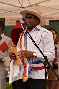 a man with a hat and a sash holding a microphone