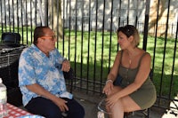 a man is talking to a woman at a picnic table