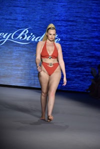 a woman in a red bikini walks the runway at miami fashion week