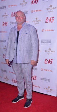 a bald man in a suit standing on a red carpet