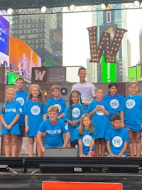 a group of children in blue t - shirts standing on stage