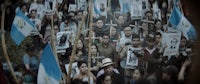 a crowd of people holding signs and flags