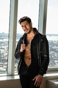 a man in a leather jacket posing in front of a window