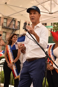 a man in a hat is speaking to a crowd of people