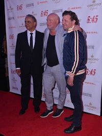 three men standing next to each other on a red carpet