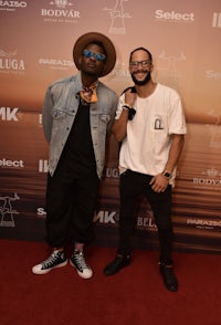 two men standing next to each other on a red carpet