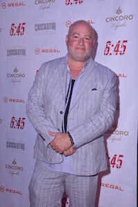 a bald man in a suit standing on a red carpet