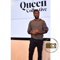 a man standing in front of a screen with the word queen collective