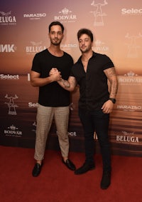 two men standing next to each other on a red carpet