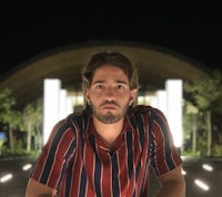 a man in a striped shirt standing in front of a building at night