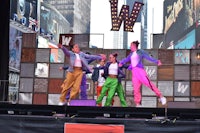 a group of people performing on stage in front of a large building