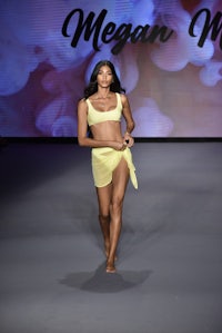 a model walks the runway in a yellow bikini