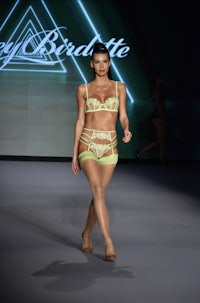 a model walks down the runway in a green bikini