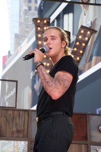 a man with tattoos singing into a microphone