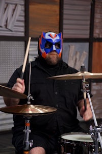 a man wearing a mask playing drums