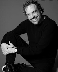 a black and white photo of a man sitting on a stool