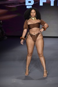 a woman in a brown bikini walks the runway