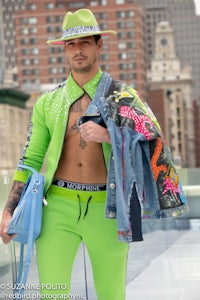 a man in a green jacket and hat is standing on a rooftop