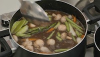 a pot of soup with vegetables in it