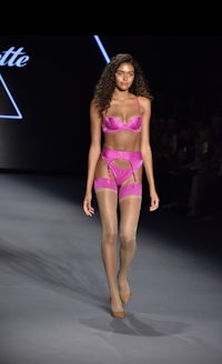 a model in pink lingerie walking down the runway