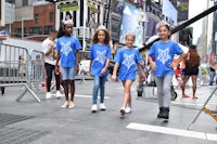 a group of girls in blue t - shirts walking down the street