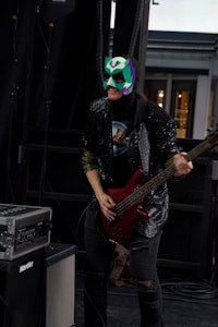 a woman wearing a mask playing a bass guitar