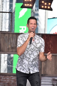 a man in a white shirt is singing into a microphone