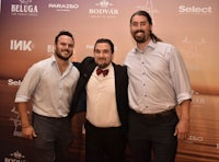 three men posing for a picture on a red carpet