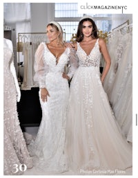 two women are posing in front of wedding dresses