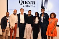 a group of people standing in front of a screen with the word queen collective