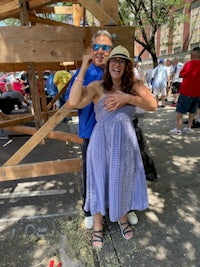 a man and woman posing in front of a wooden structure