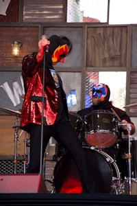 a man in a red jacket is playing drums