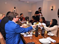 a group of people sitting around a table and drinking wine