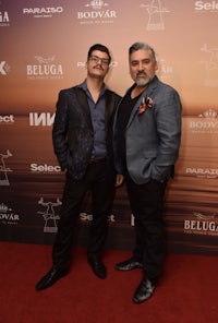 two men standing on a red carpet at an event