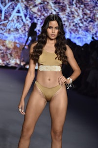 a model wearing a gold bikini on the runway