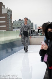 a man in a plaid suit walking down a runway