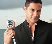 a man holding a microphone in front of a body of water