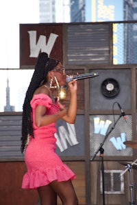 a woman in a pink dress singing into a microphone