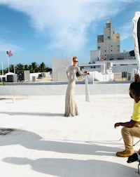 a woman in a dress is standing on a roof with a camera