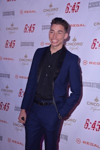 a man in a blue suit standing on a red carpet