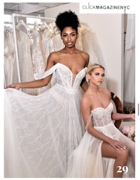 two women in white wedding dresses posing in front of a dress rack