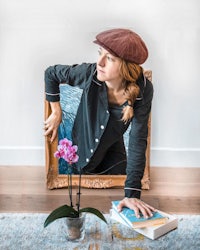 a woman leaning over a frame with a flower in it