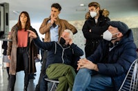 a group of people wearing face masks in front of a tv